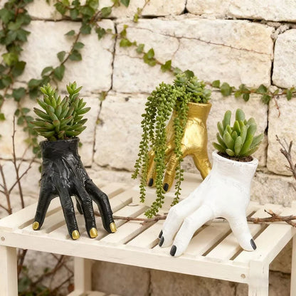 Three unique hand-shaped planters with succulents on a stone wall background