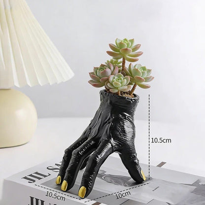 Black hand-shaped planter with succulents on a white surface with measurement details.